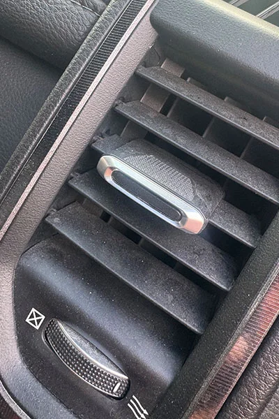 Faded gray air vent trim before and after professional restoration showing deep black factory finish