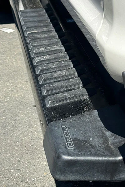 Faded black running board step trim before professional restoration