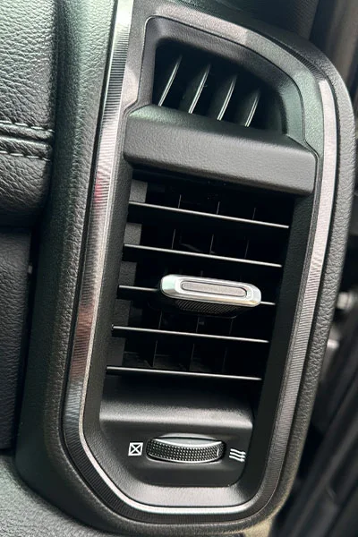 Gray air vent trim after restoration service showing deep black factory finish