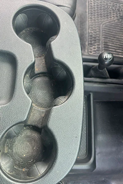 Faded gray cup holder trim before professional restoration in San Jose
