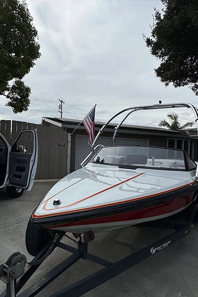 Mobile boat detailing service at customer home showing white speedboat with red stripes on trailer next to Nor Bay service van